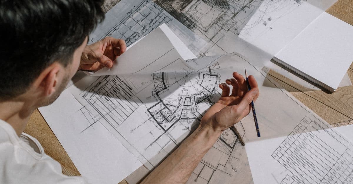 An architect sketching over detailed architectural blueprints.